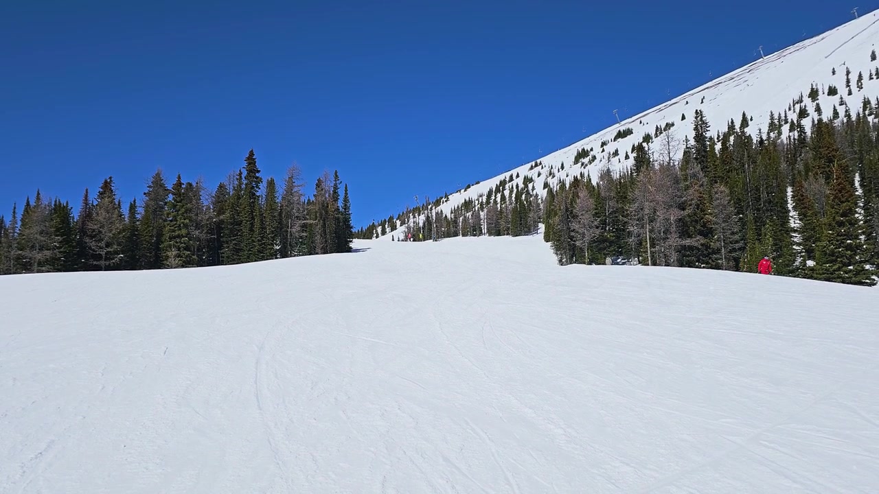 Canadian Rockies ski resort view in Banff shows sweeping snowy slopes, mountain tracks, and dramatic peaks in bright winter daylight.