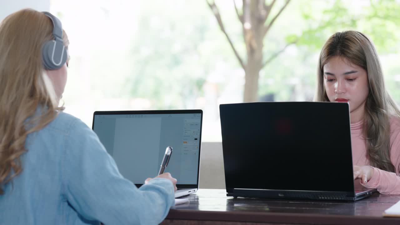 Two Asian girls student partners are working on a laptop help study together