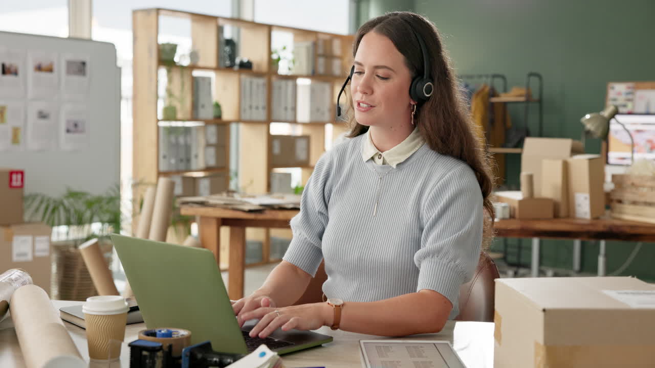 Woman working on laptop in office with headset