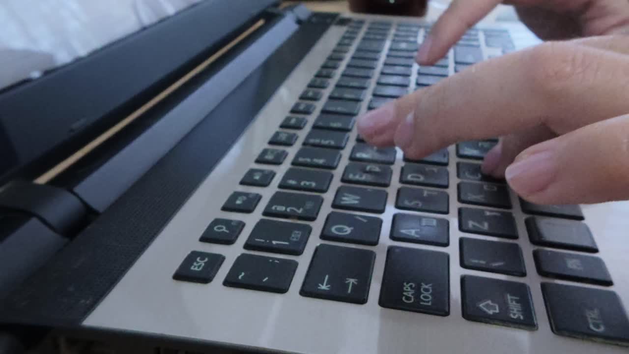 Front perspective of hands typing on a laptop keyboard. Home office productivity, digital workflow