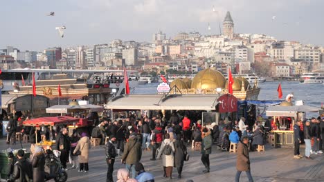 crowded waterfront in istanbul with galata tower in the background