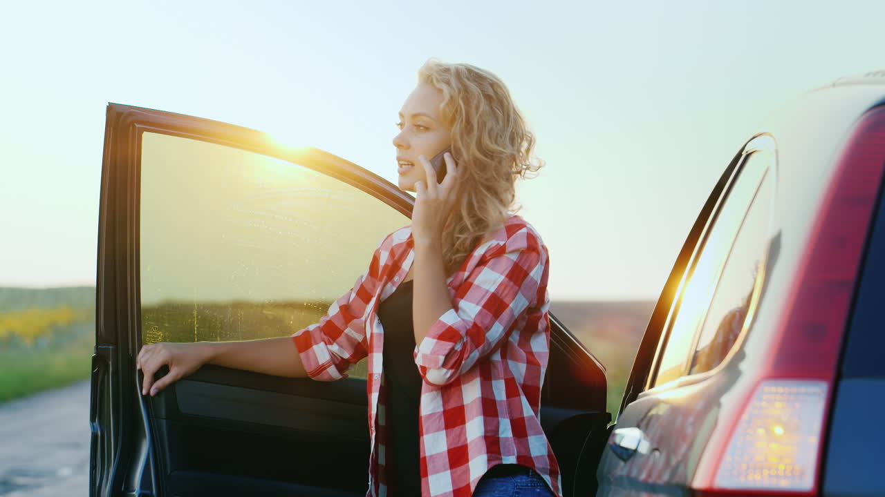 una mujer está hablando por teléfono junto a un coche
