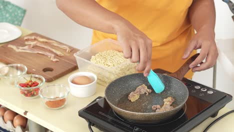 person frying meat in a pan on an induction cooktop