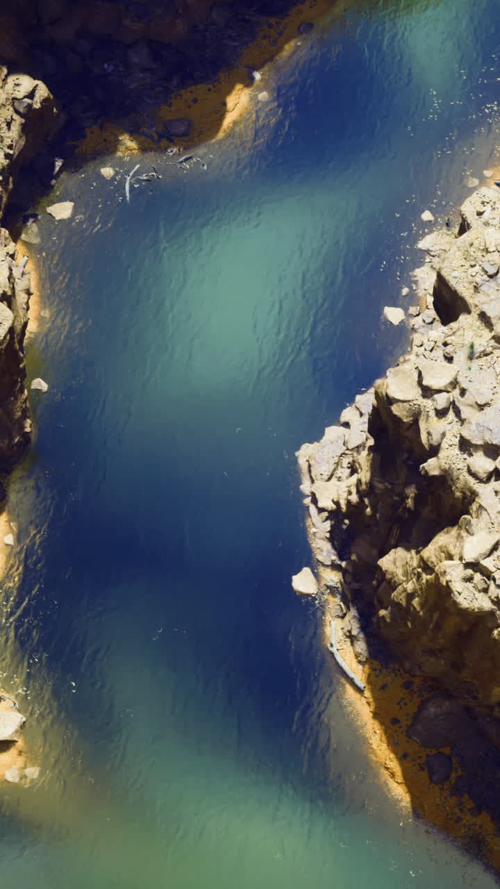 Fiume sereno che serpeggia attraverso un canyon roccioso sotto un cielo limpido