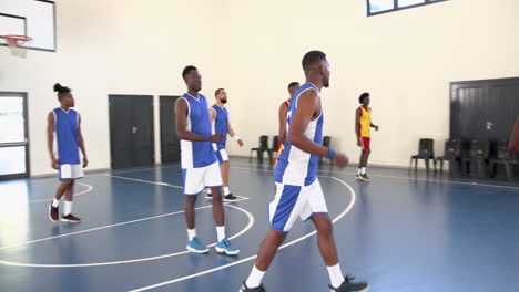 multiracial male basketball players playing basketball, passing and throwing basketball in gym