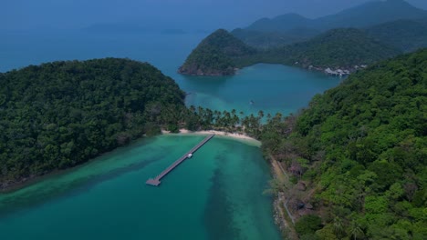 koh chang's idyllic landscape, featuring lush greenery, a pristine beach, and a tranquil pier extending into the turquoise waters. fabulous aerial view flight drone shot footage from above