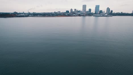 establishing-shot-above-water-with-milwaukee,-WI,-USA-downtown-skylines