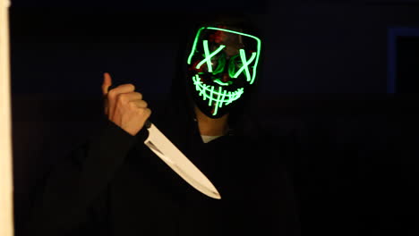 a scary slasher killer in a generic anonymous halloween horror mask pulling a knife on his murder victim