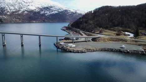 scenic orbiting aerial view of arctic centre resort and gratangen bridge alongside calm fjord waters in norway