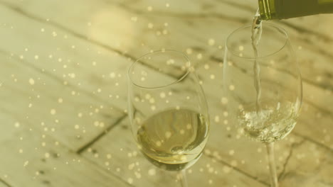 composite of white wine being poured into glasses over wooden background