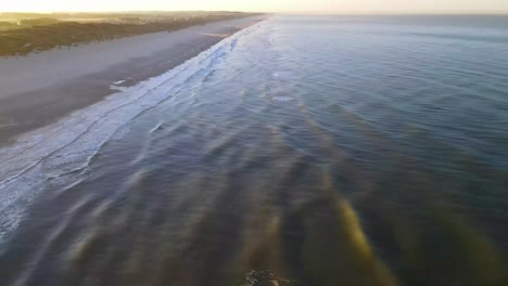 aerial view of rolling waves and sunrise at the ocean close to løkken by the north sea, denmark