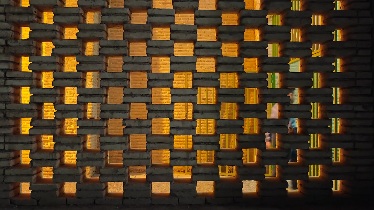 Person Walking Past a Decorative Brick Wall with Warm Backlighting