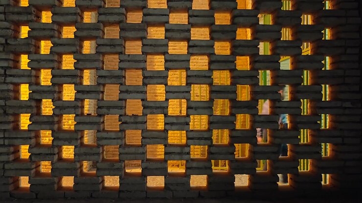 Person Walking Past a Decorative Brick Wall with Warm Backlighting