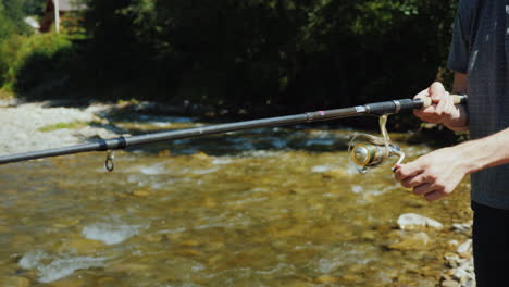 a young man is fishing around a small river a side view only the hands are visible in the frame