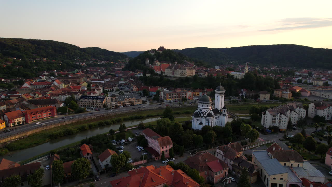 Vista aérea da cidade romena de Sighisoara ao pôr do sol, às margens do rio.
