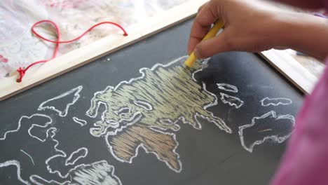 child drawing a world map on a chalkboard