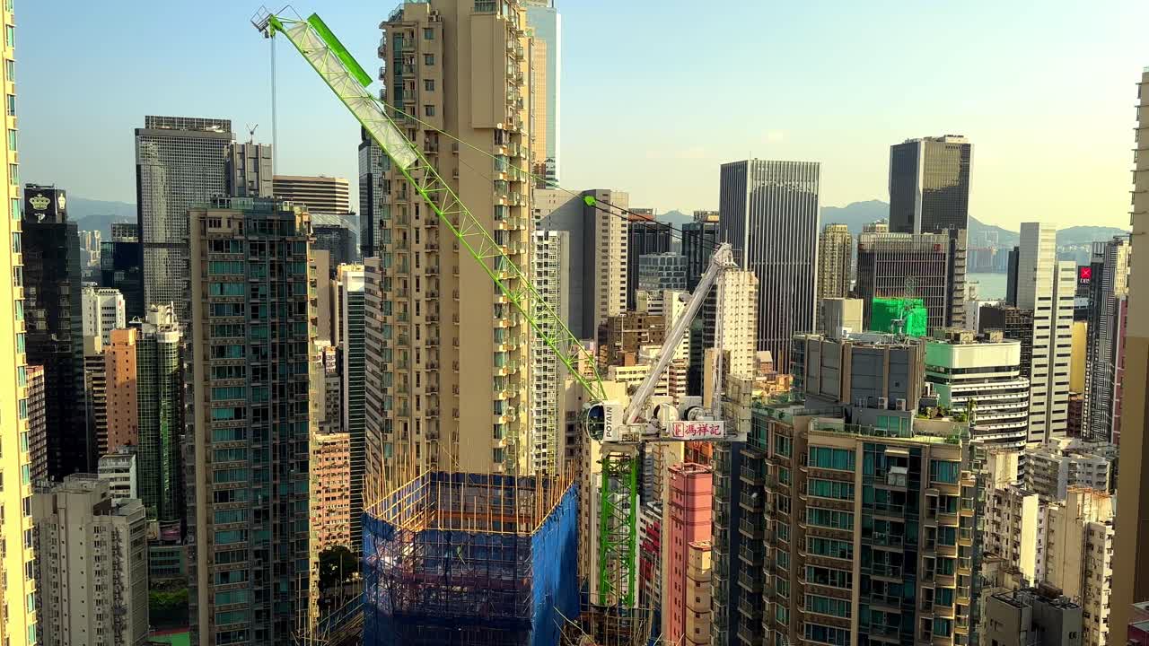 Stationary Tower Crane on Skyscraper Construction Site Surrounded by Residential Buildings in Hong Kong's Concrete Jungle