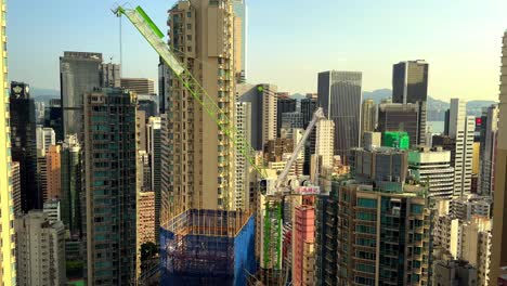 Stationary Tower Crane on Skyscraper Construction Site Surrounded by Residential Buildings in Hong Kong&#039;s Concrete Jungle