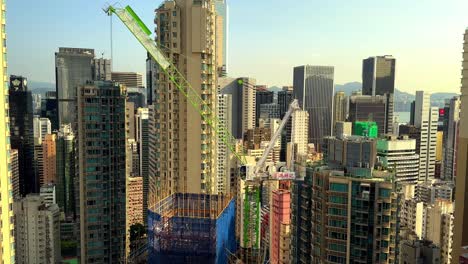 stationary tower crane on skyscraper construction site surrounded by residential buildings in hong kong's concrete jungle