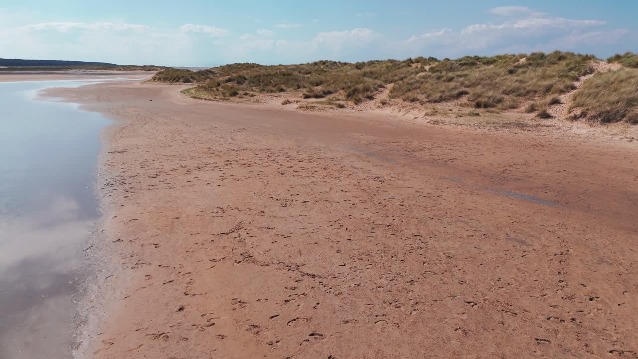 The calm holkham bay coastline with soft sandy beach and gentle tide, aerial view