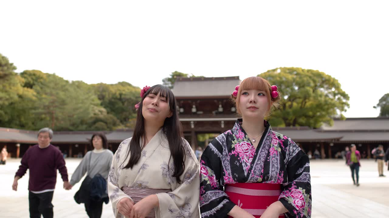 Due donne che indossano kimono tradizionali sono in piedi insieme nel cortile di un santuario storico giapponese