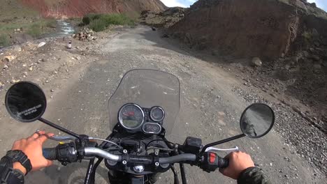 Point-of-view-shot-of-a-bumpy-bike-ride-through-a-scenic-mountain-road-on-a-bright-sunny-day-with-dry,-vibrant-mountain-in-surrounding