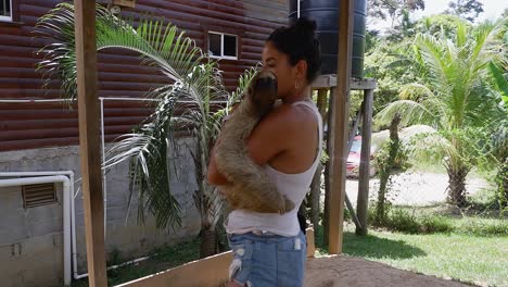 latina woman cuddles with cute 3-toed sloth in nature park in honduras