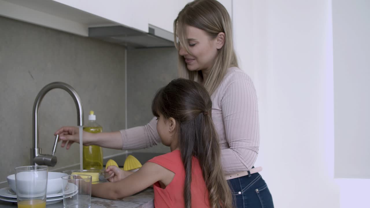 chica adorable ayudando a mamá a lavar los platos