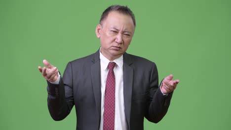 mature confused japanese businessman shrugging shoulders