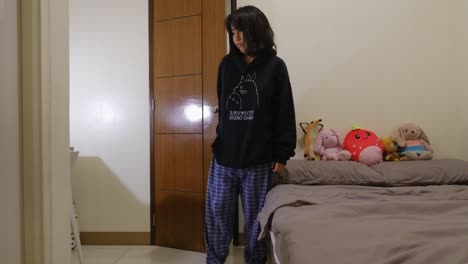 Una-Chica-Asiática-Soñolienta-En-Pijama-Entra-Al-Dormitorio,-Apaga-Las-Luces-Y-Duerme-En-La-Cama