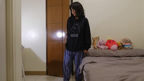 sleepy asian girl wearing pajamas enters the bedroom, turns off the lights, and sleeps in bed