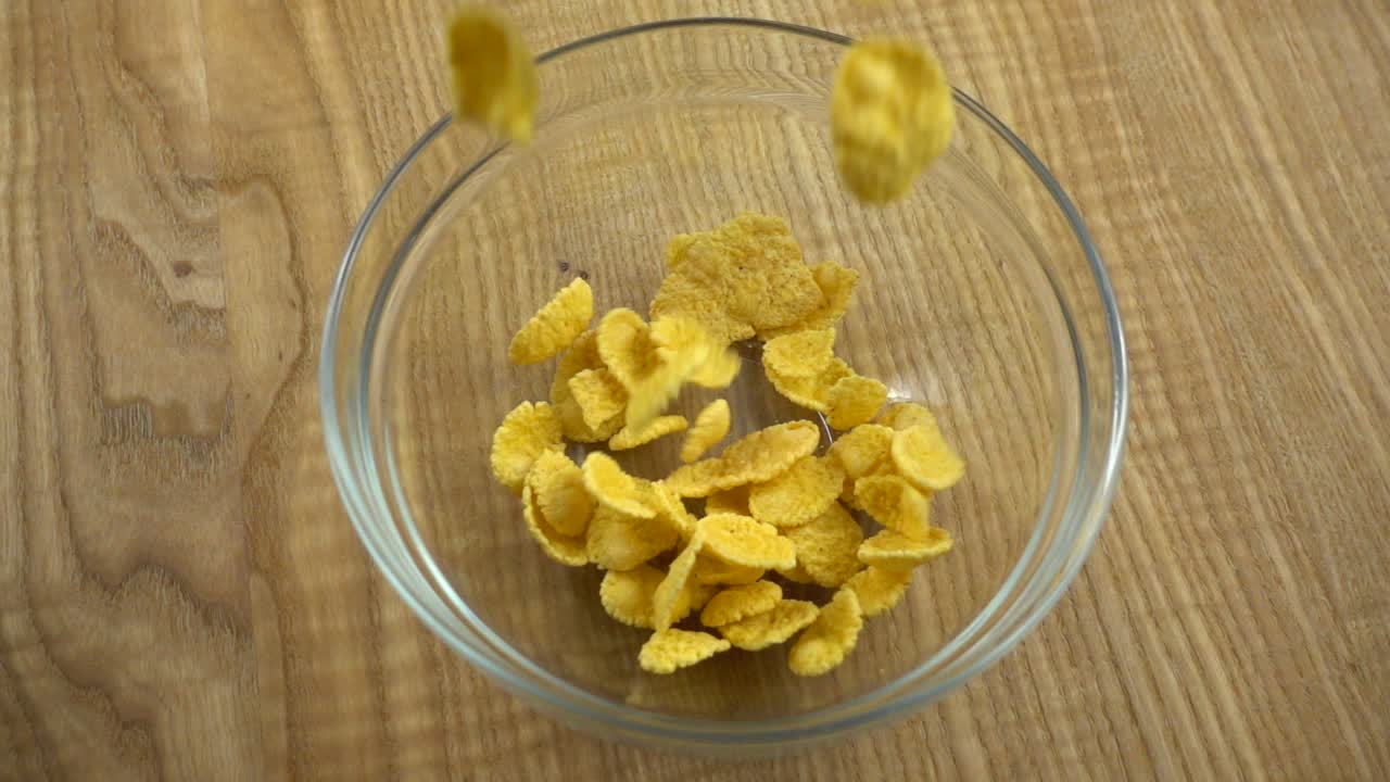 I corn flakes vengono versati in una ciotola di vetro. Slow motion.