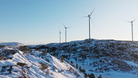 winter landscape with wind turbines in mountains of bessaker, norway - drone pullback