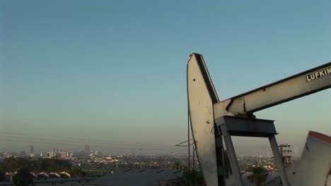 un pozo de petróleo bombea petróleo con un extenso paisaje suburbano detrás 1