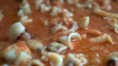 appetizing-squid-relying-on-tomato-during-the-preparation-of-fideua-seen