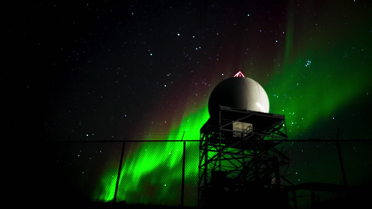 Nordlys bag tårn i arktisk tundra
