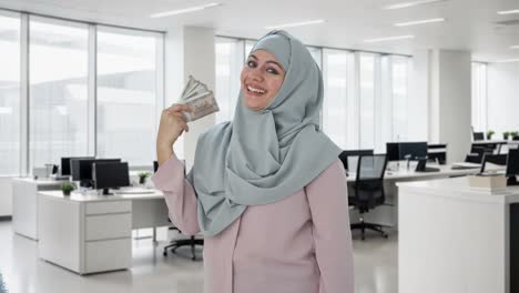 Happy-Muslim-businesswoman-using-money-as-fan