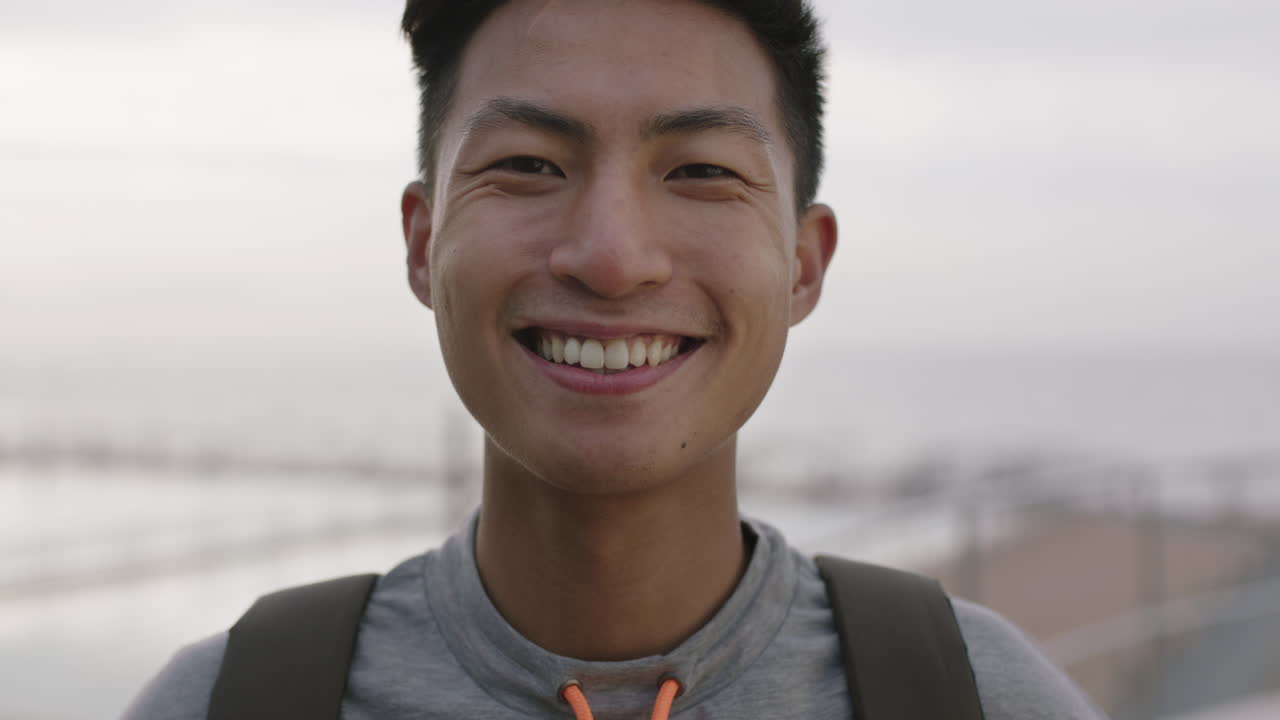 매력적 인 젊은 아시아 남자 의 포트레이트 가 가 ⁇ 게 미소 짓고 있다