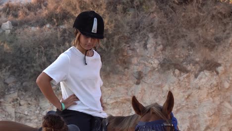 an instructor teaches a young girl how to ride a horse