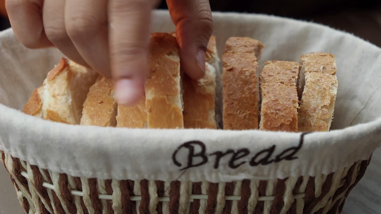 Hand reaching for bread slices from a basket