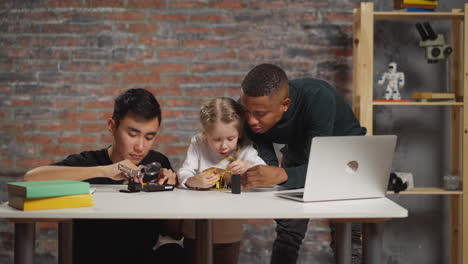 afro-american teacher helps schoolgirl assemble device