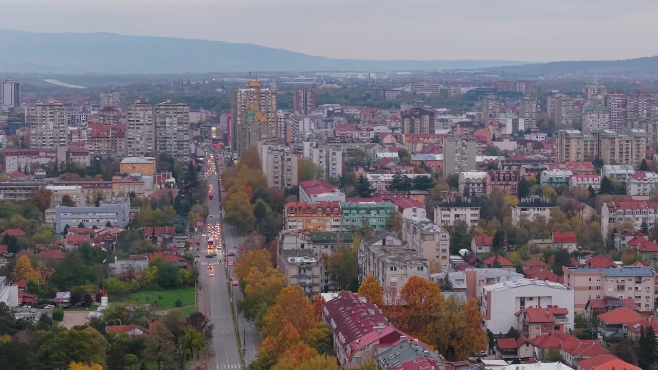 Um drone sobrevoa Niš, capturando a paisagem urbana e as estradas movimentadas, destacando o fluxo do trânsito e o ritmo dinâmico da cidade vista de cima.