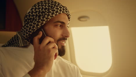 arab businessman talking cell phone in airplane closeup. confident man traveling