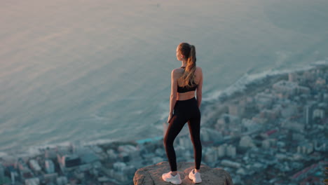 Mujer-Sana-En-La-Cima-De-La-Montaña-Mirando-La-Tranquila-Vista-Del-Océano-Al-Atardecer-Niña-Parada-En-El-Borde-Del-Acantilado-Disfrutando-De-La-Libertad-Contemplando-El-Viaje-A-La-Cumbre