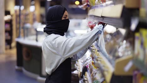 Mujer-Con-Pañuelo-Negro-Trabajando-En-La-Tienda,-Inspeccionando-Los-Estantes-De-La-Tienda.
