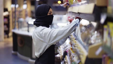 woman in black scarf working in store, inspecting shelves in store