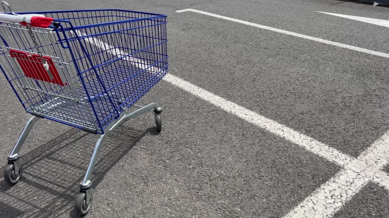 side view of metallic hypermarket shopping cart in parking lot