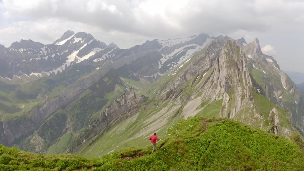 un hombre con una chaqueta roja corriendo en la cima de una montaña