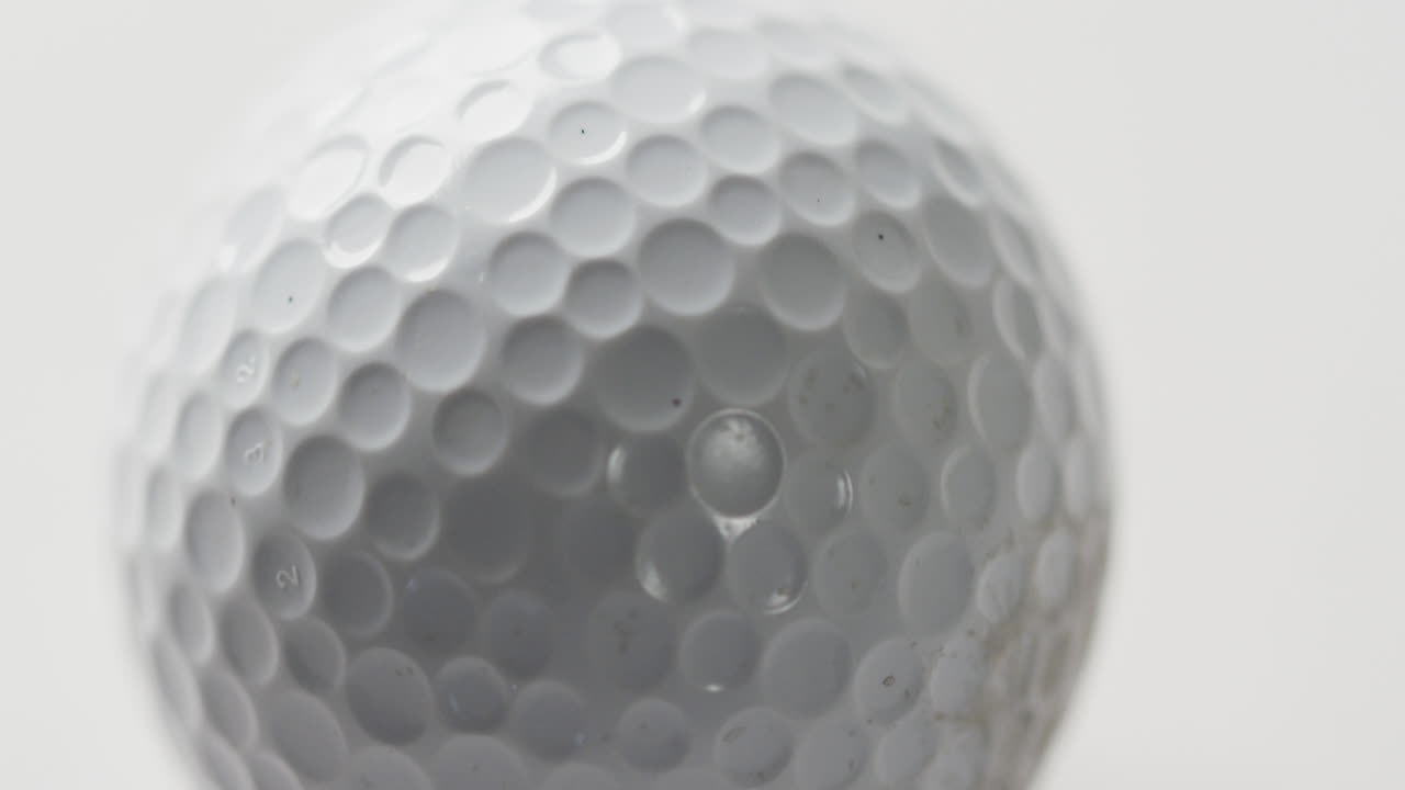 Close-up van golfbal op witte achtergrond, slow motion, ruimte voor tekst