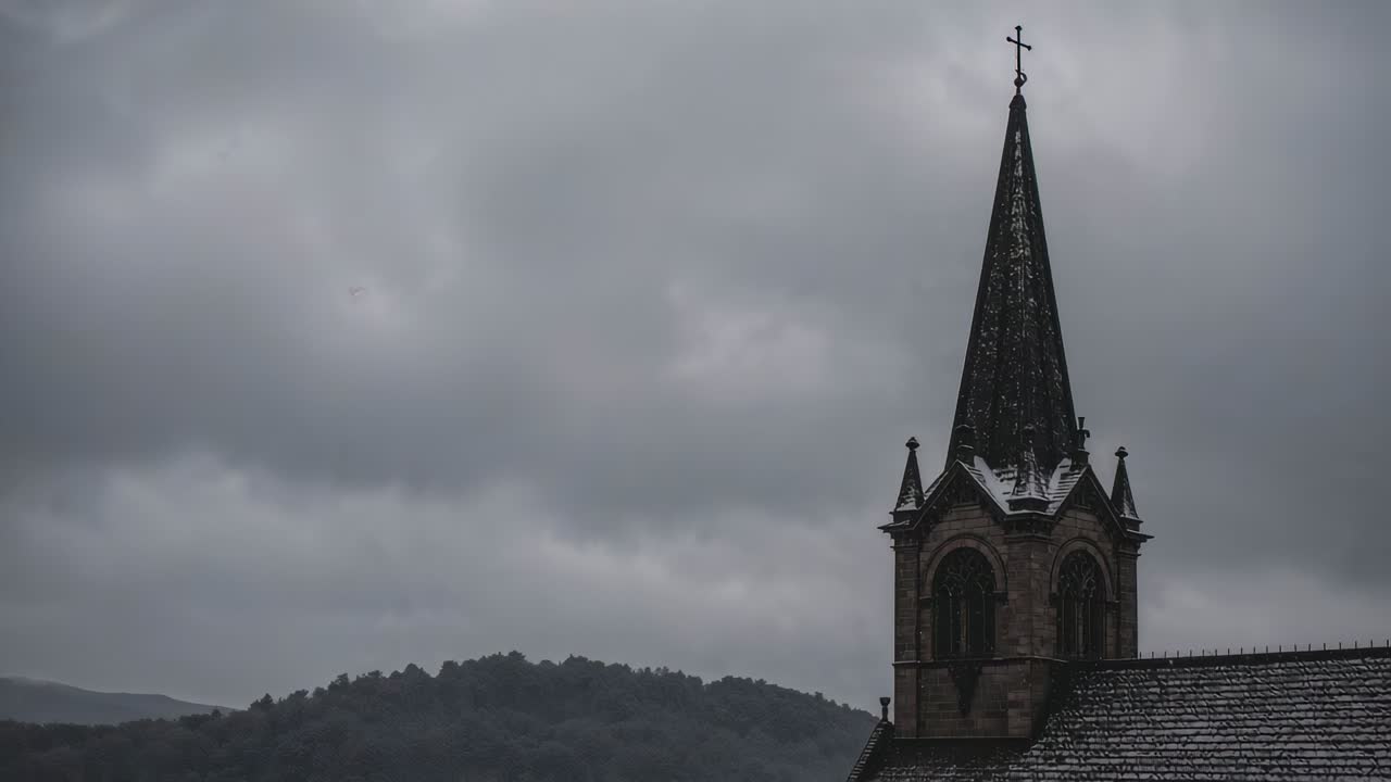 Shifting low clouds drifting across hills, stone steeple topped by cross holding snow, copy space